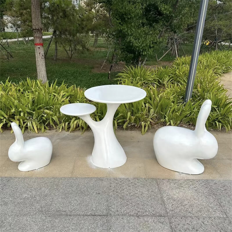 Complete set of white rabbit chairs and tree table placed in an outdoor park