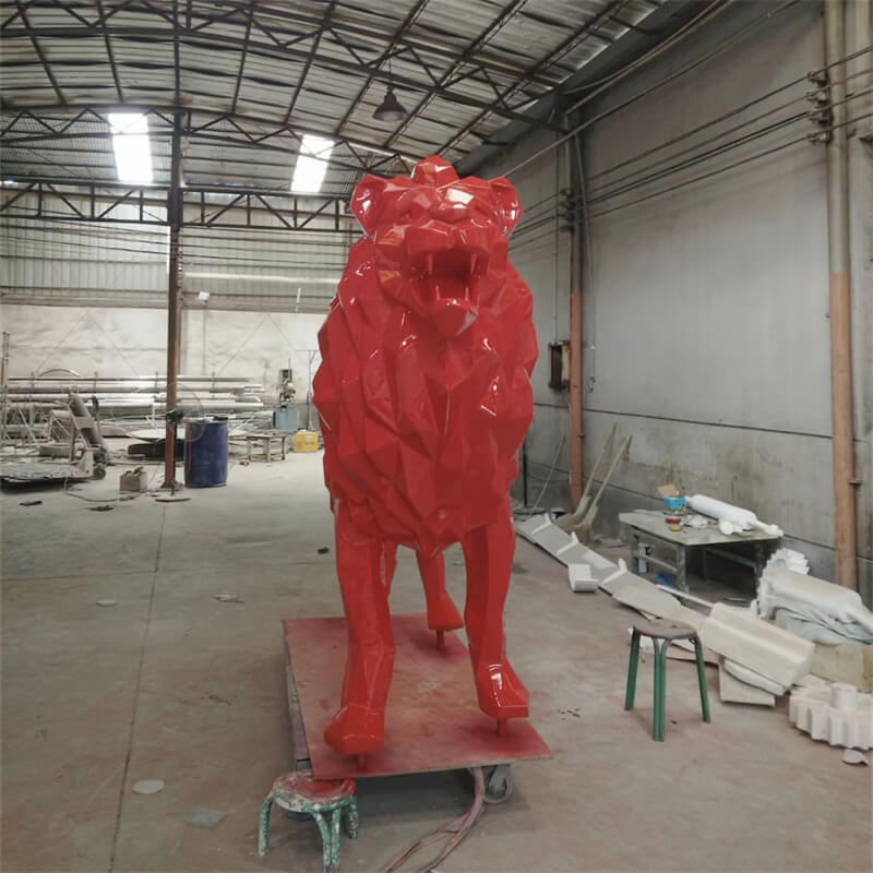 Bright red geometric cut‑surface fiberglass lion sculpture with a roaring pose. A finished factory product shot.
