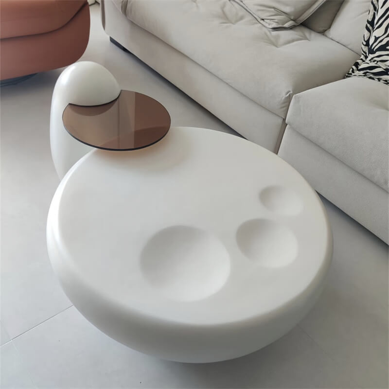 White paw‑shaped fiberglass coffee table with an irregular glass side table beside sofas in a luxury living room