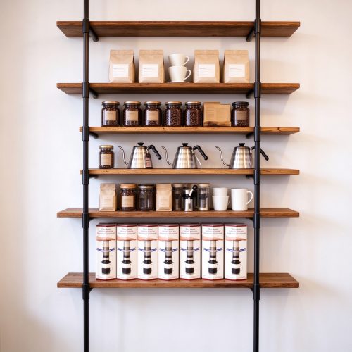 Wall-mounted coffee shop shelving rack with black metal frame and wood shelves, left 45 degree view