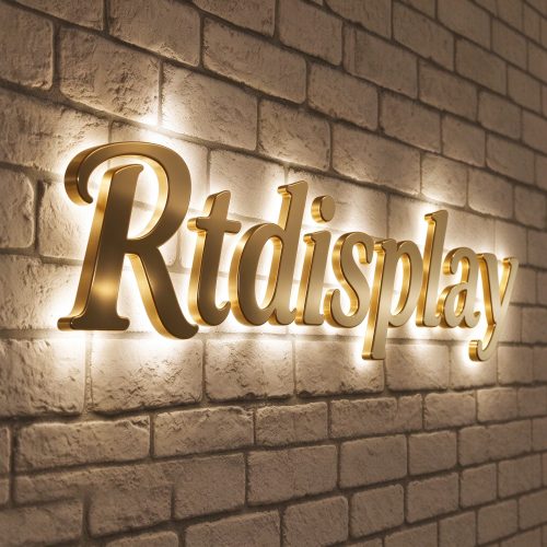 Brushed gold 3D backlit channel letters on white brick wall, right 45 degree angle